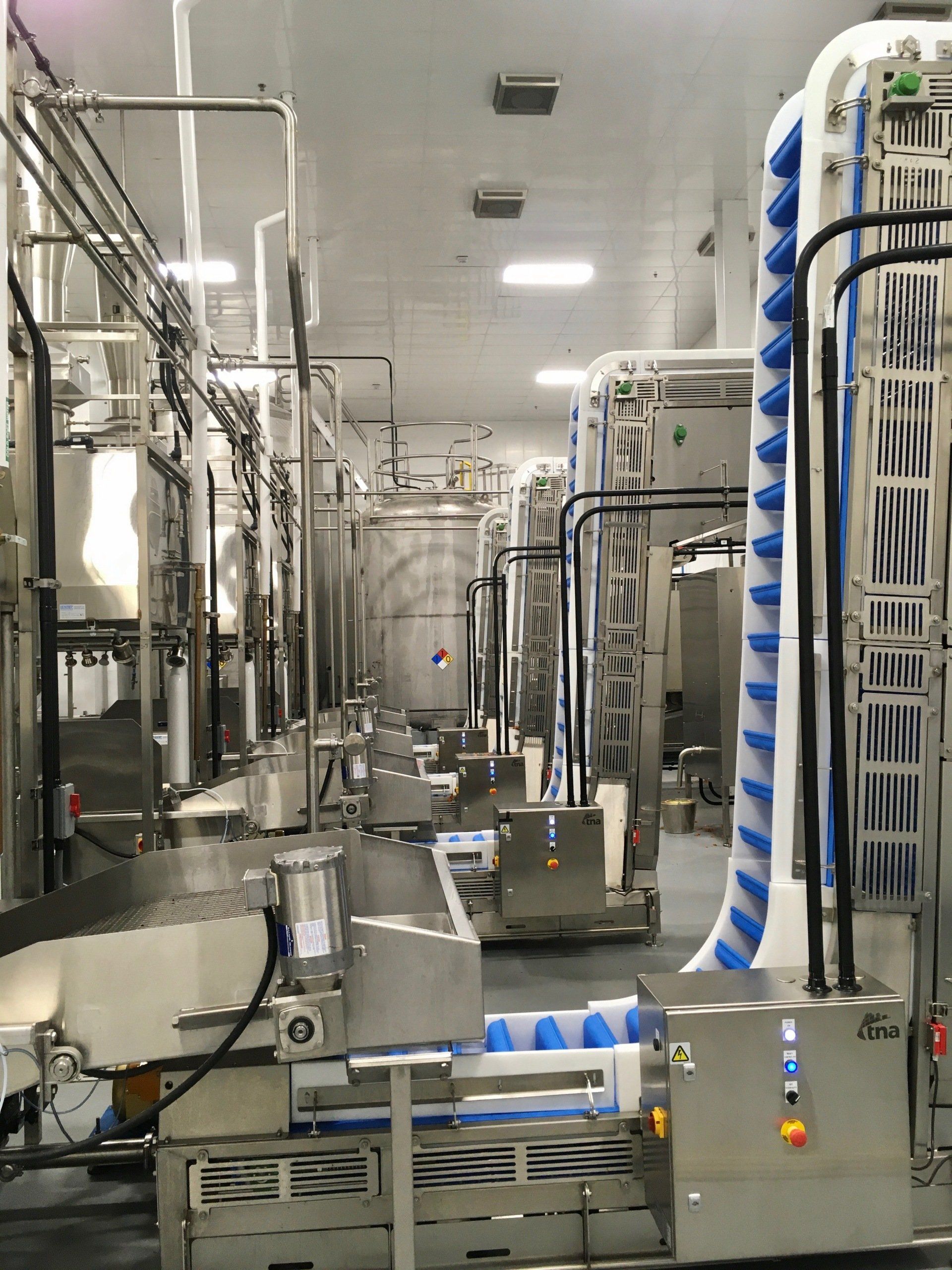 Industrial food processing facility, stainless steel machinery, conveyor belts, cool lighting.