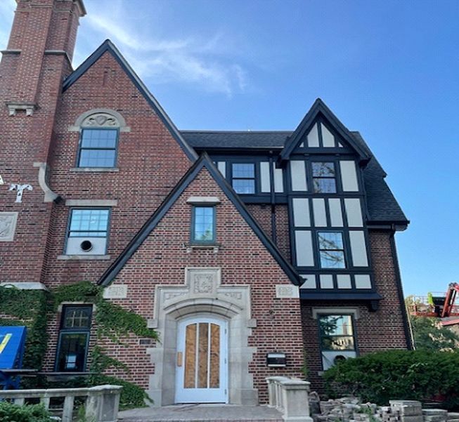 Brick Tudor style house with multiple gables and a white door under an arched entrance.