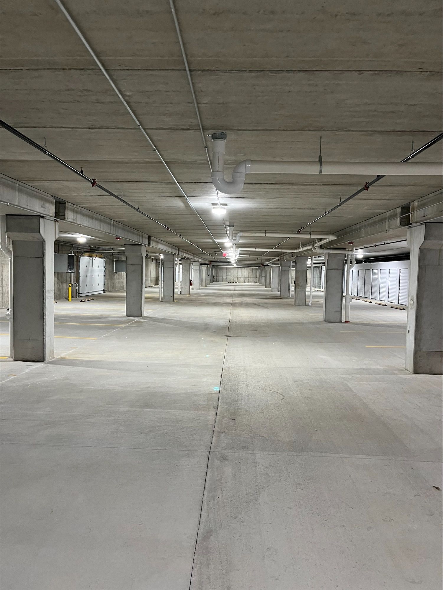 Empty concrete parking garage with support columns and overhead lighting.