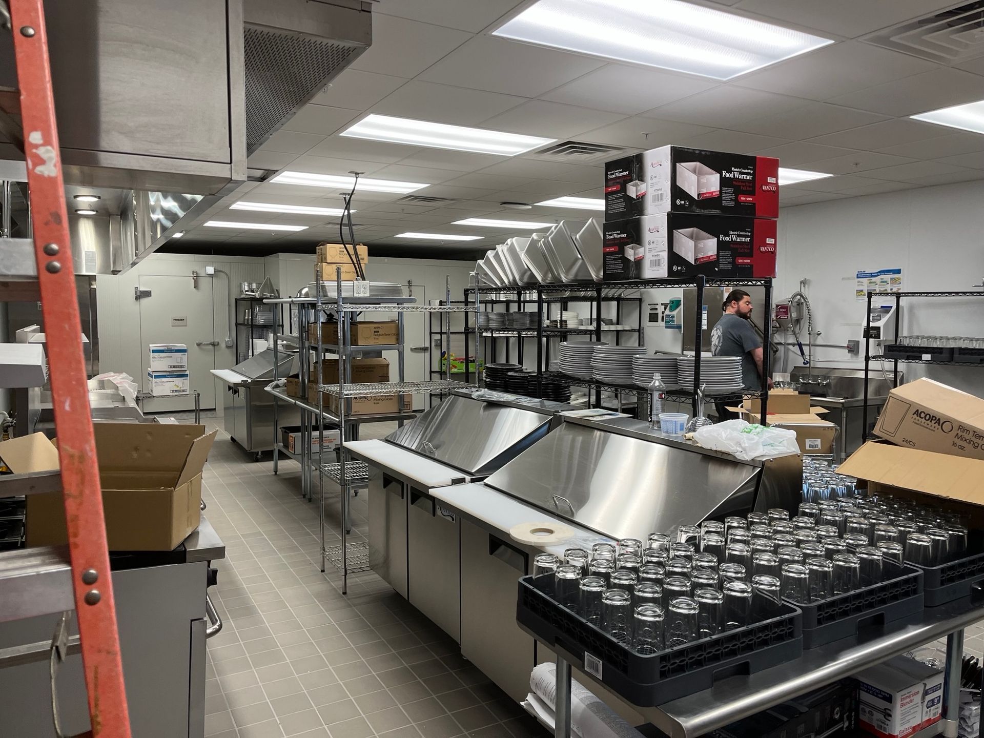 Commercial kitchen with stainless steel equipment and a person standing in the background.