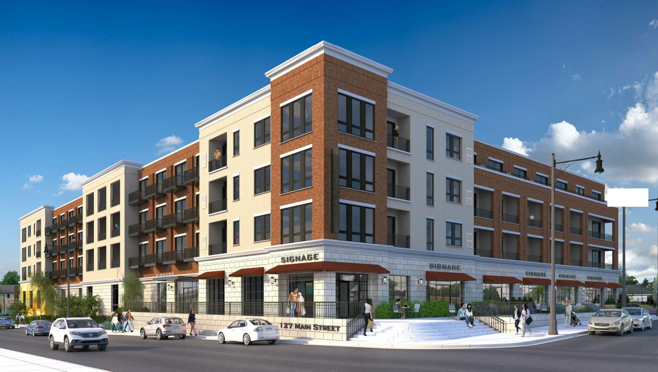 Multi-story brick and stucco building with retail storefronts, balconies, and cars on the street.
