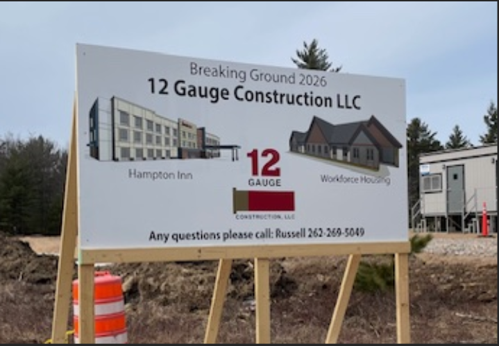 Construction sign for 12 Gauge Construction LLC at a site, with a house rendering and orange traffic barrel.