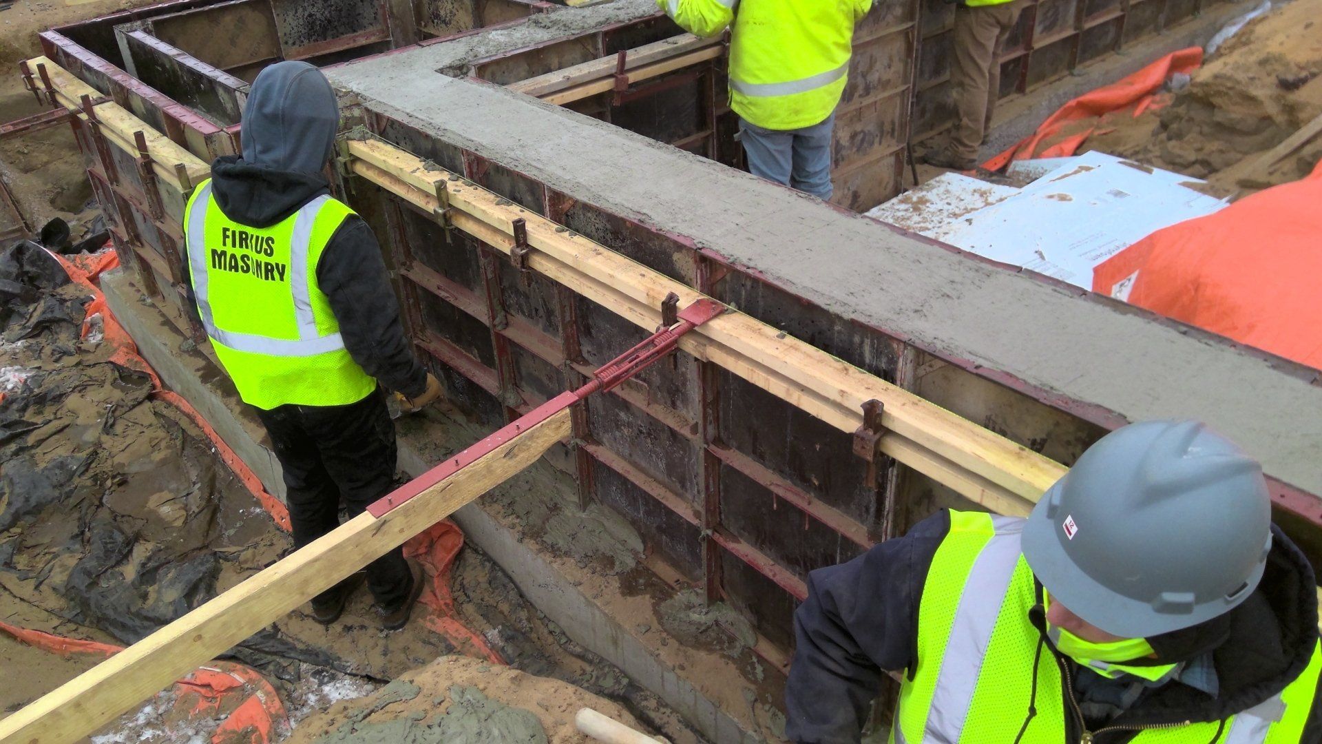 Construction workers pouring concrete into forms at a construction site.