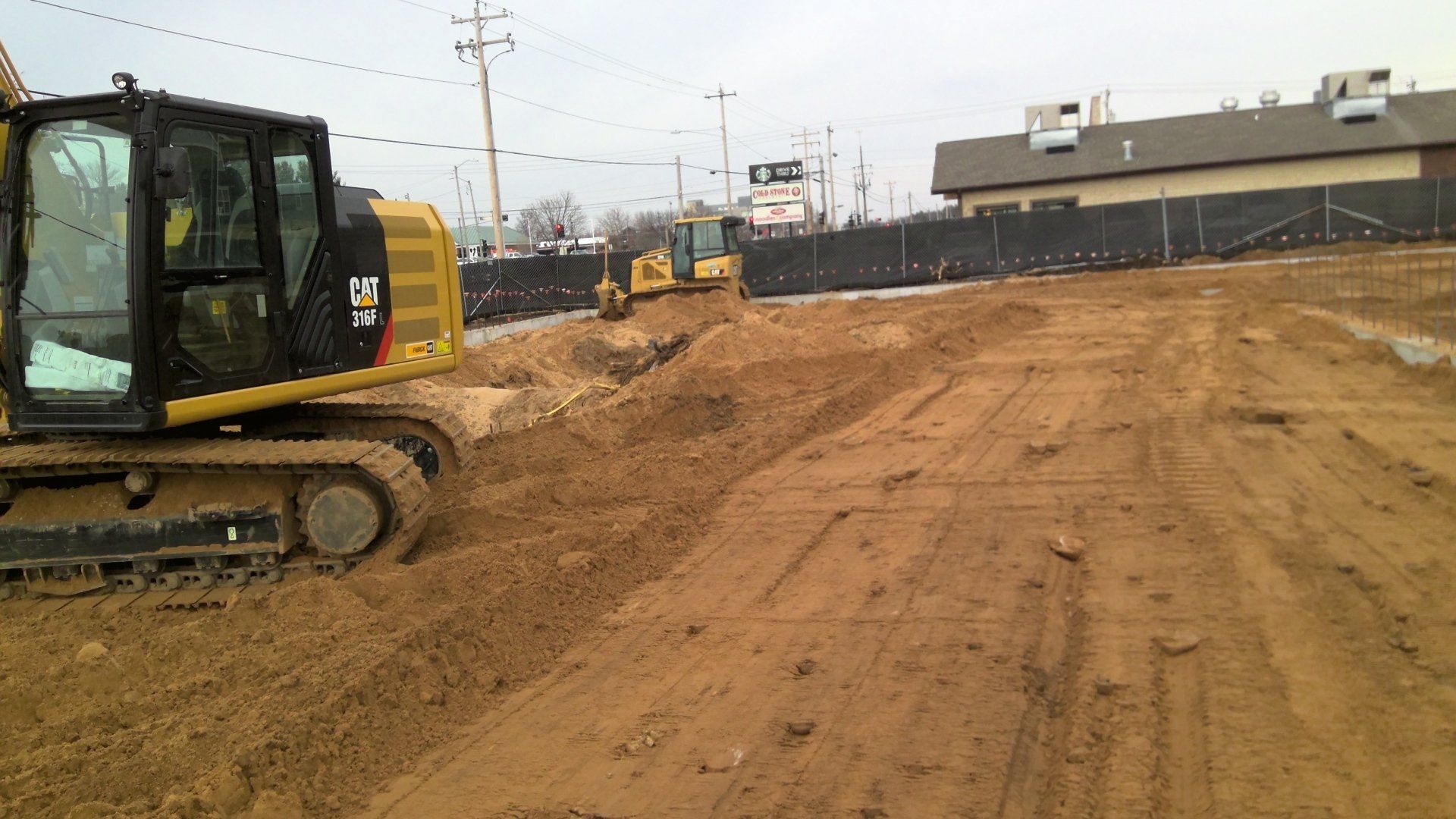 Construction site: Excavators moving dirt, preparing for building, cloudy day.