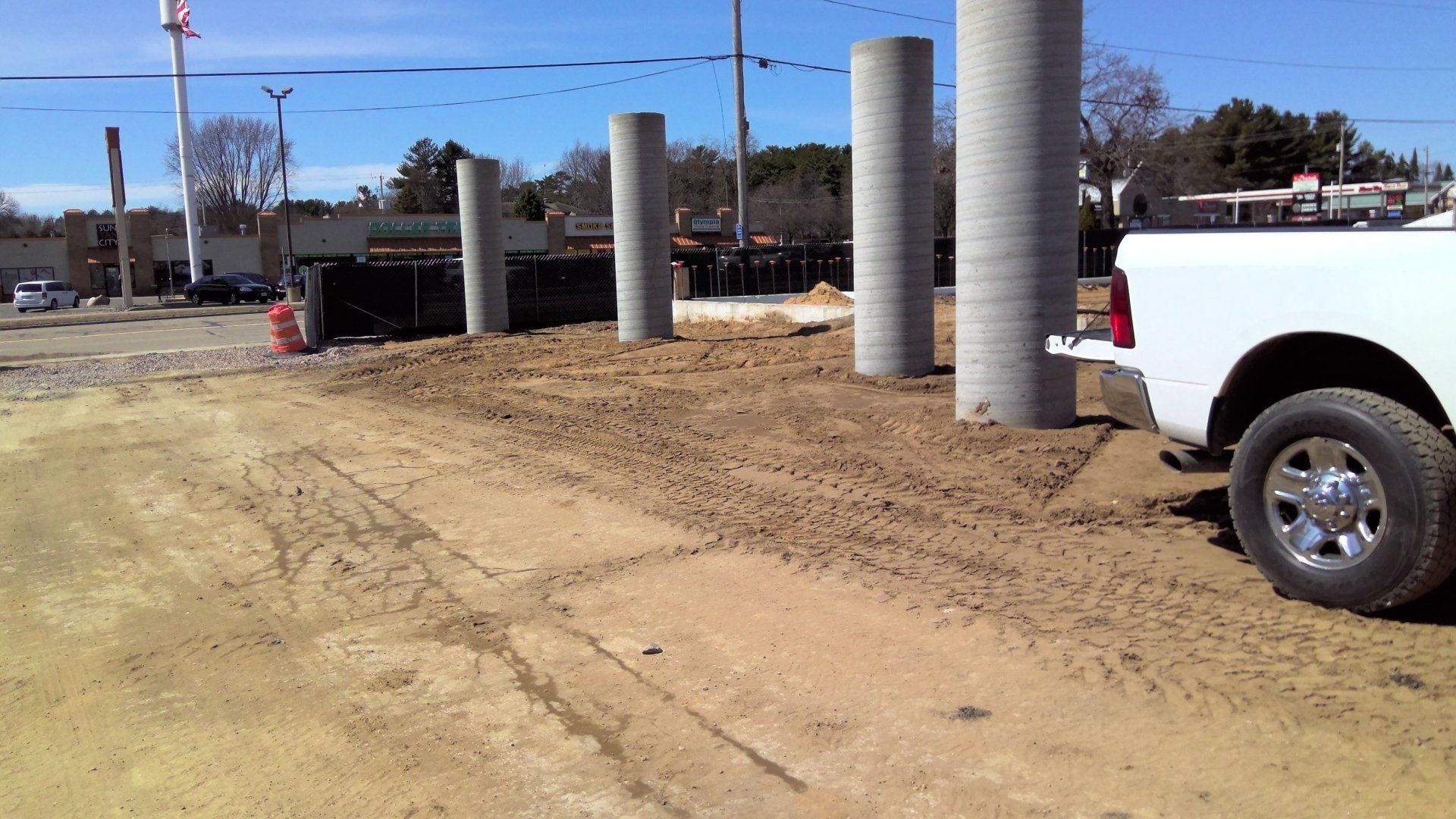 Construction site with concrete pillars and a white pickup truck.