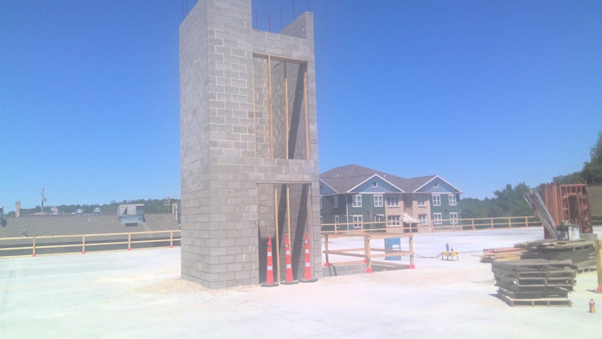 Construction site with a tall, concrete block structure; blue sky, sunny day.