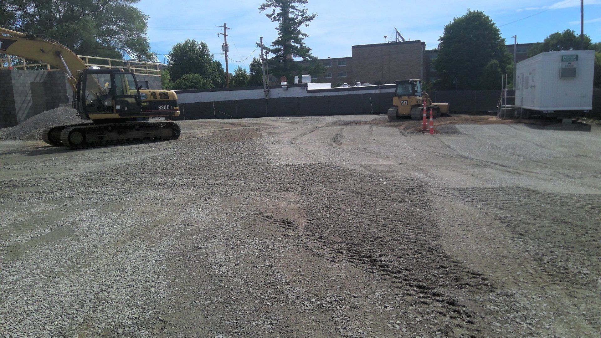 Construction site with excavator and small bulldozer on gravel.