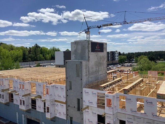 Construction site with a crane; wood framing and concrete structure against a blue sky.