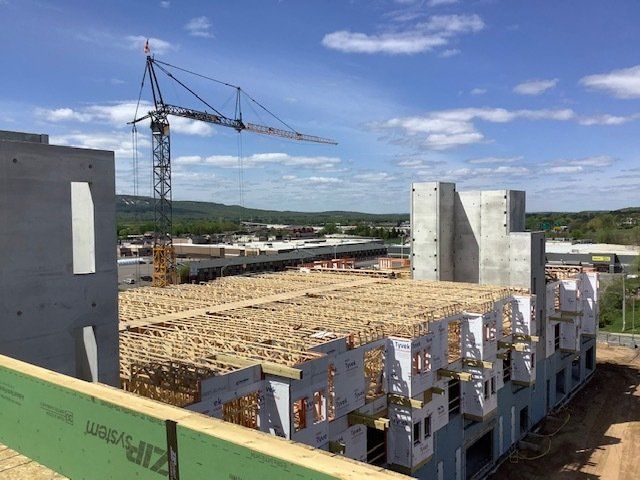 Construction site with crane, wooden framework, and concrete walls against a blue sky.