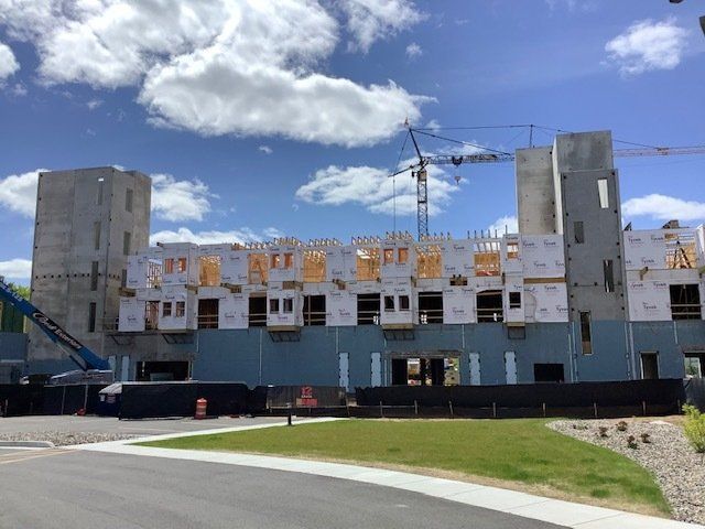 Building construction site with concrete and wooden frames, under a blue sky with clouds.