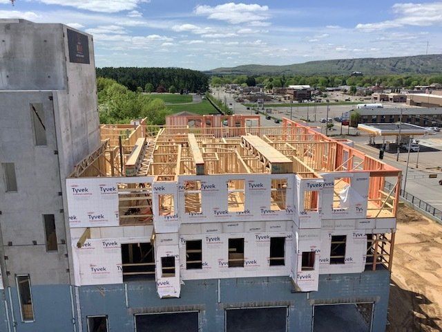 Building construction, wood framing and concrete walls. A partially built structure with a view of a road and trees.