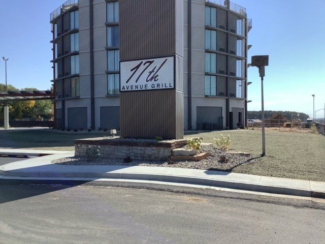 Sign for 17th Avenue Grill restaurant in front of a modern building with blue sky.