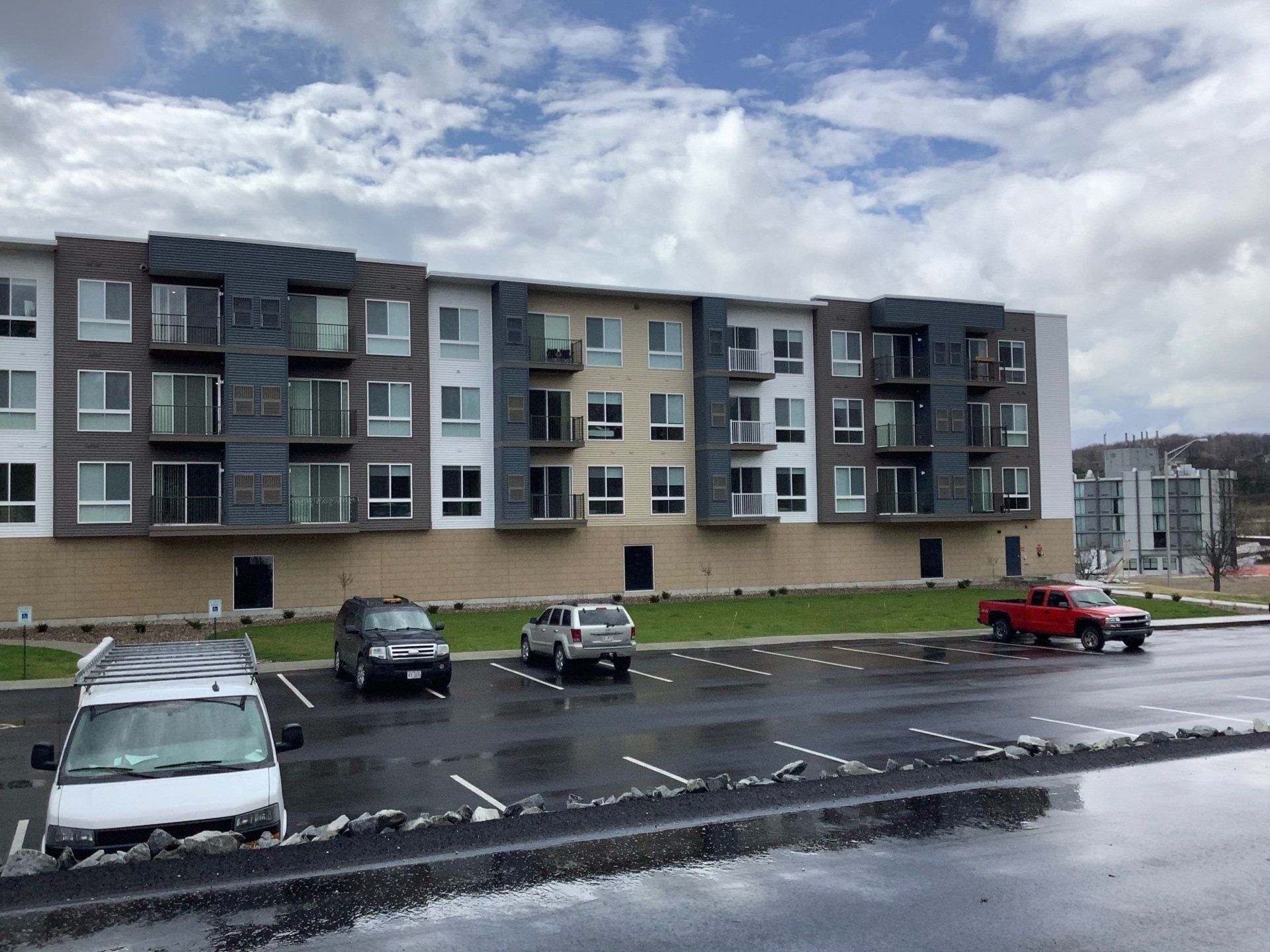 Apartment building with cars parked in front on a cloudy day.