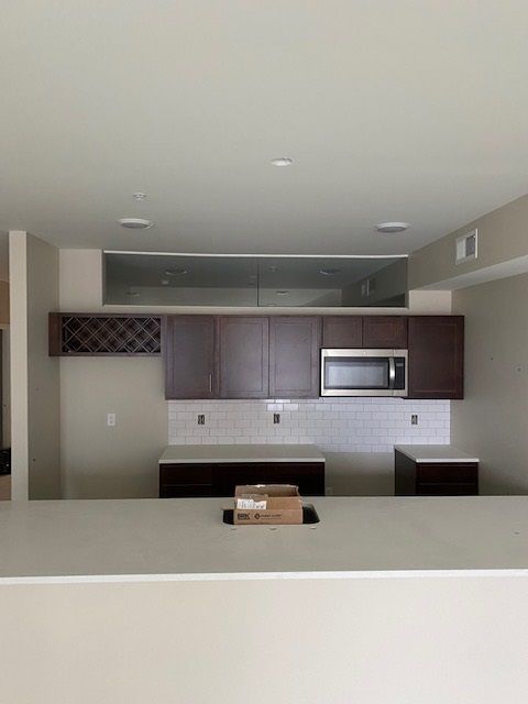 Kitchen with dark brown cabinets, a microwave, and a white countertop.
