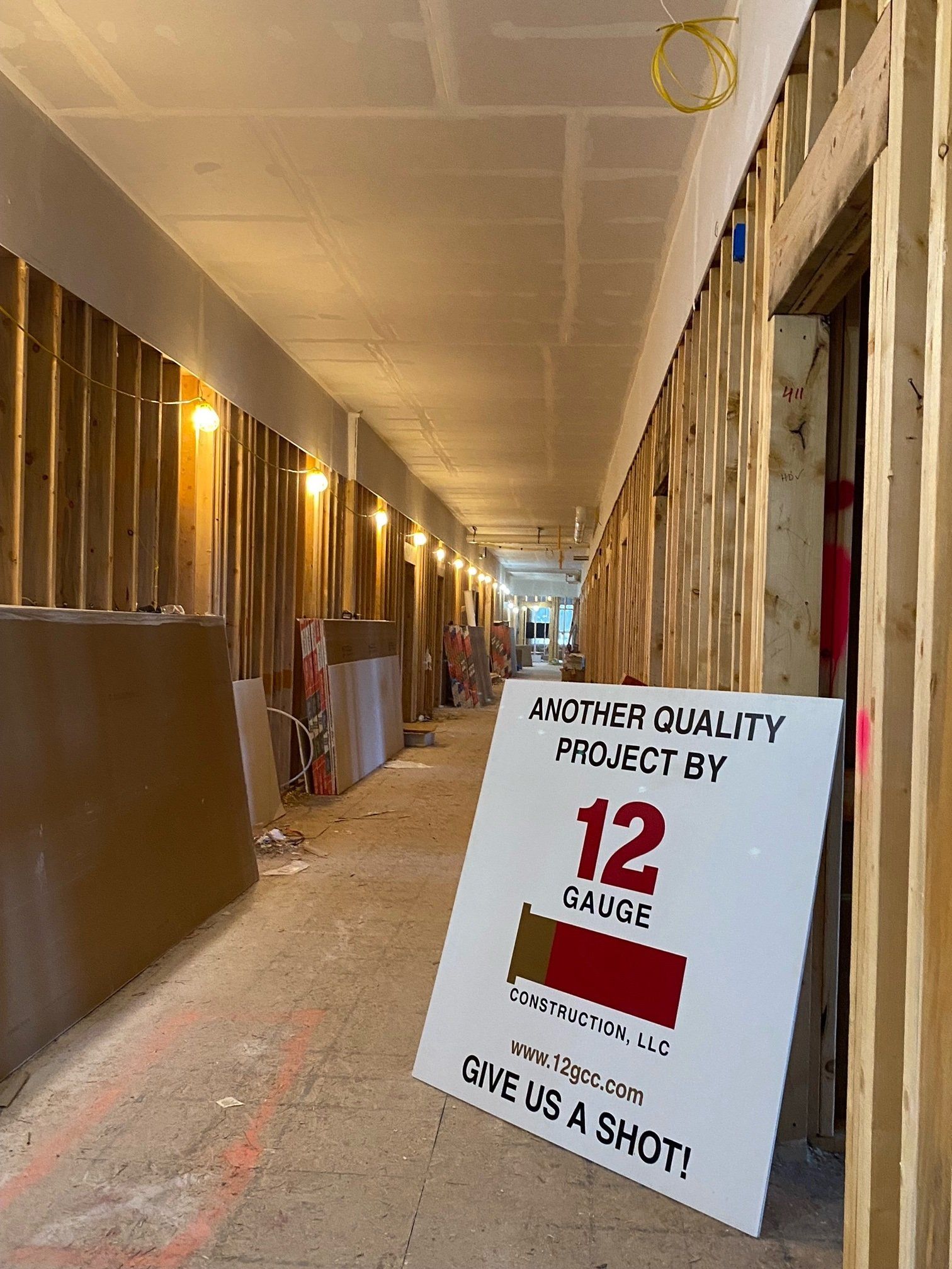 Construction site hallway with exposed wood framing and drywall. A sign reads 