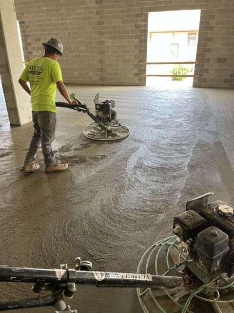 Construction worker smoothing concrete floor with a power trowel in a building.