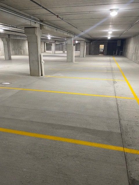 Empty, well-lit concrete parking garage with yellow parking space lines.