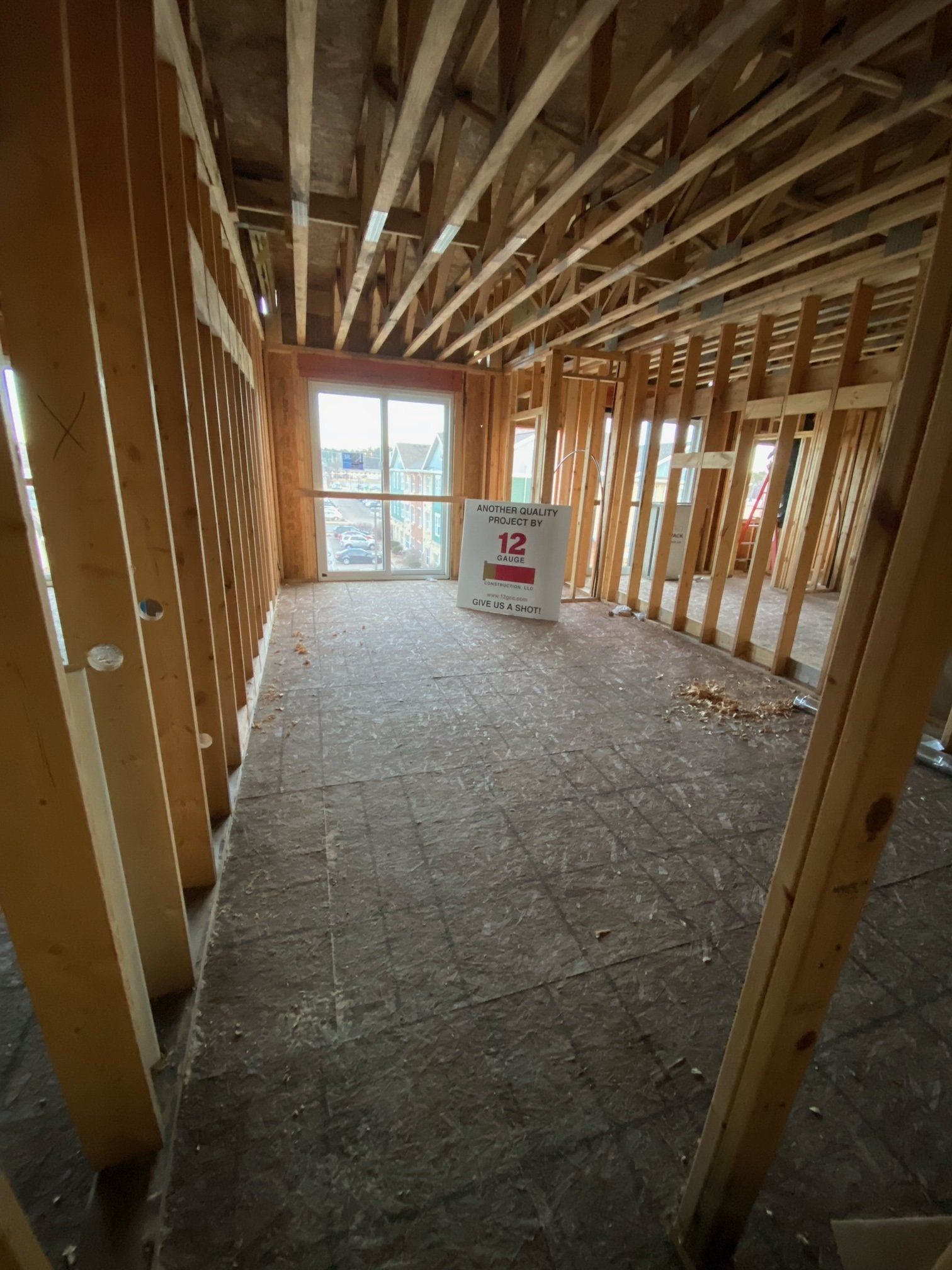 Interior of a room under construction, with wooden frame walls, floor, and ceiling, and a doorway.