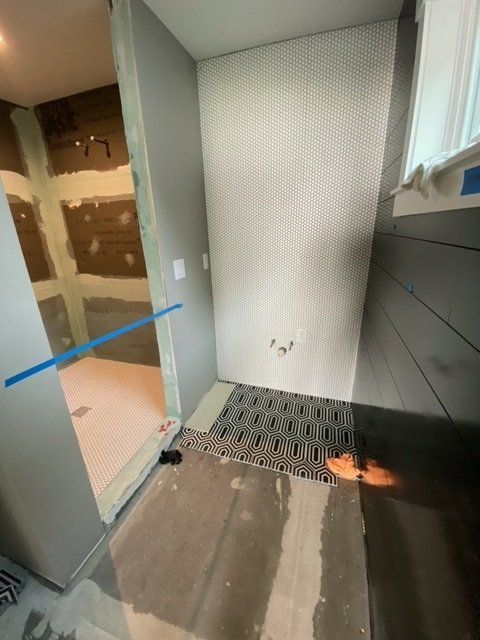 Bathroom under construction with gray walls, white penny tile, and patterned floor tile.