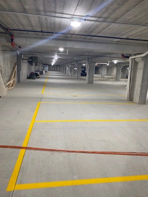 Empty concrete parking garage with yellow parking space lines and overhead lighting.
