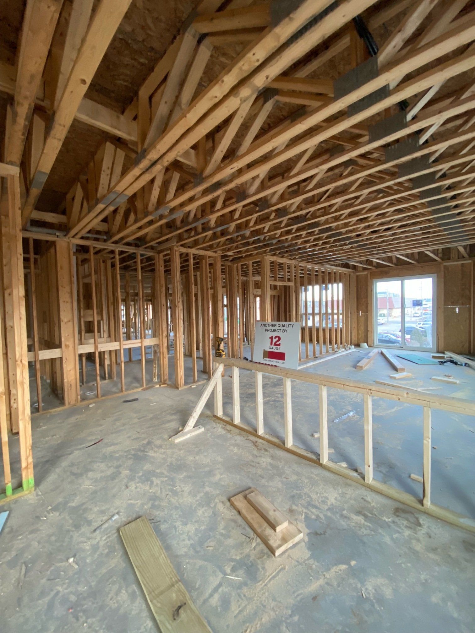Interior of a house under construction; wooden framework visible. Studs, beams, and rafters define the structure.