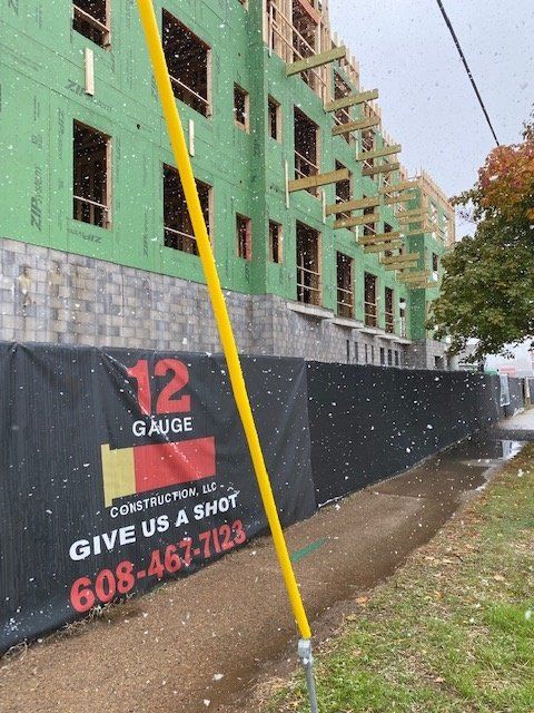 Construction site with a black fence and a yellow pole. Building has exposed framing.