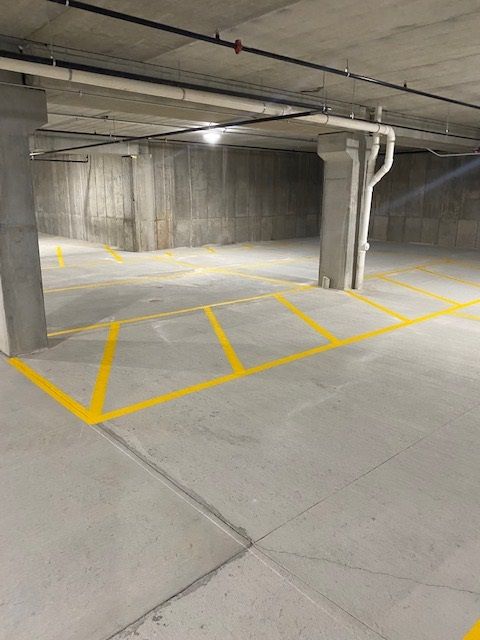 Empty parking garage with yellow painted parking space lines on a concrete floor and pillars.