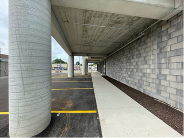 Concrete columns and a covered walkway next to a parking lot.