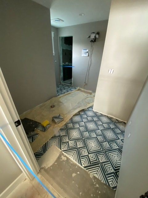 Bathroom hallway under renovation with patterned tile, partially installed.