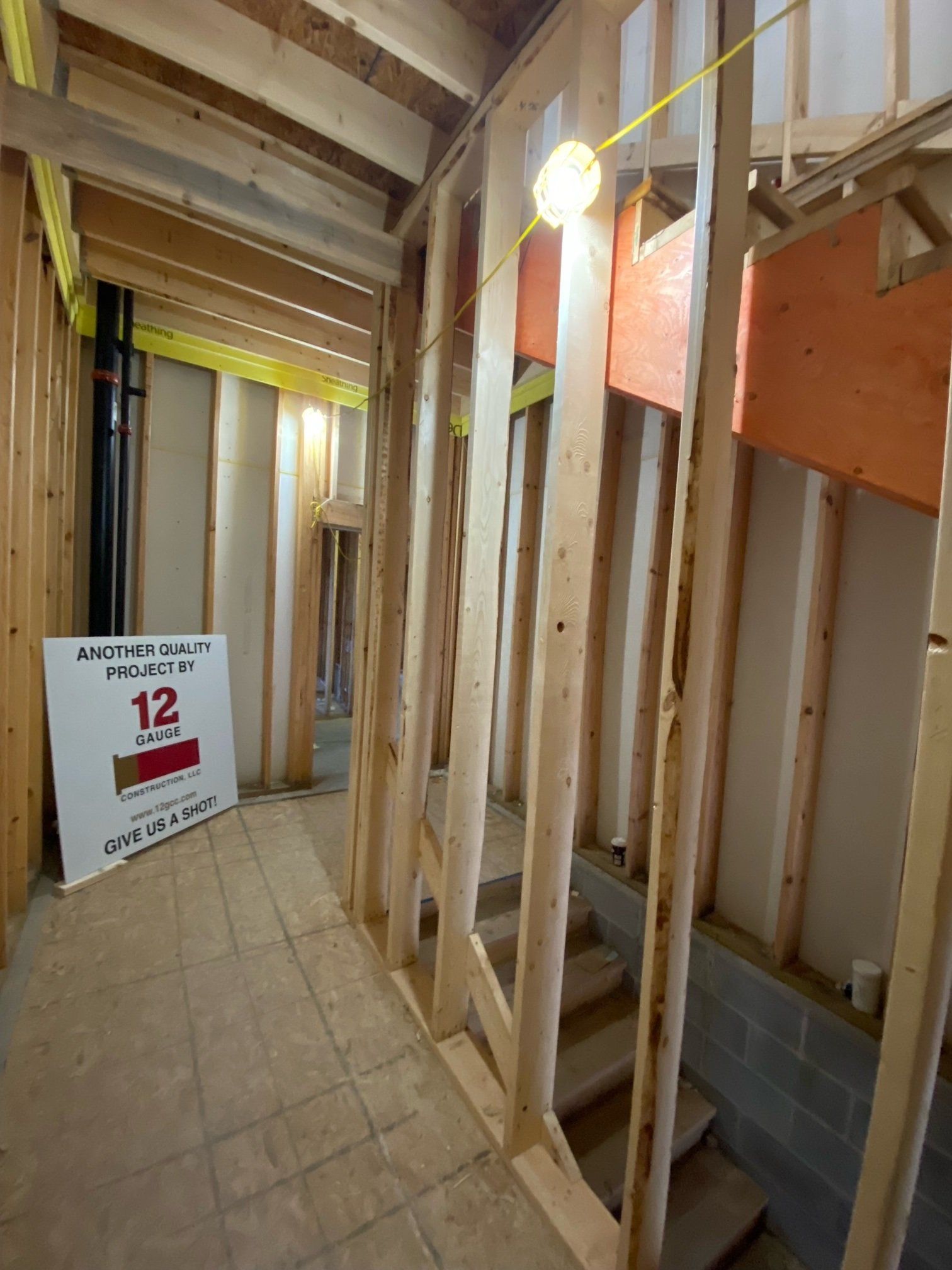 Interior view of a building under construction, showing wooden frames, stairs, and a hallway.