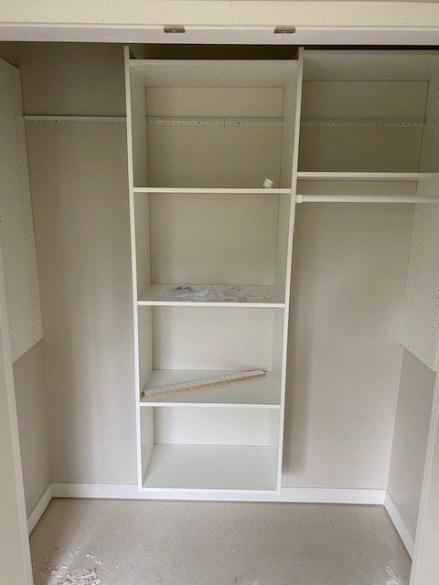 Empty closet with shelves, hanging rods, and off-white walls.