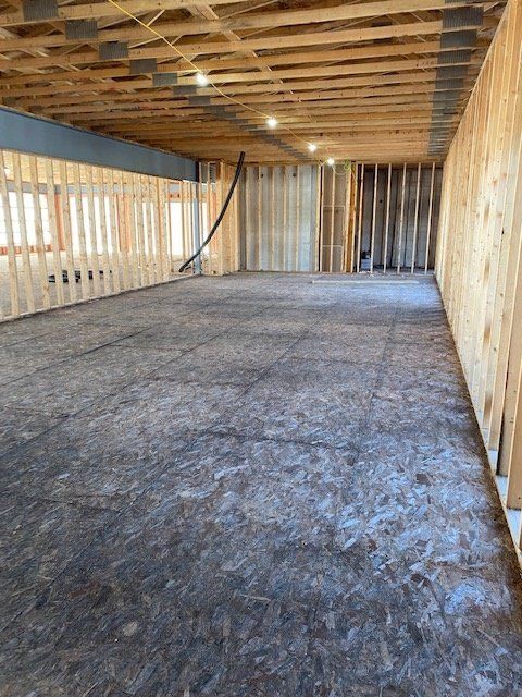 Interior view of a room under construction with exposed wooden framing and flooring.