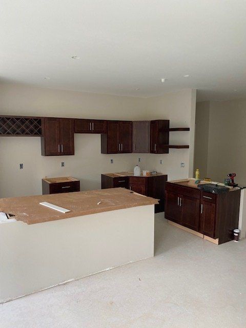 Kitchen under construction with dark brown cabinets, a white island, and light walls.