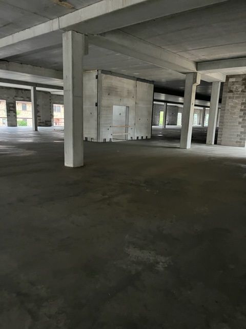 Empty concrete interior of a building, showing pillars and unfinished walls.