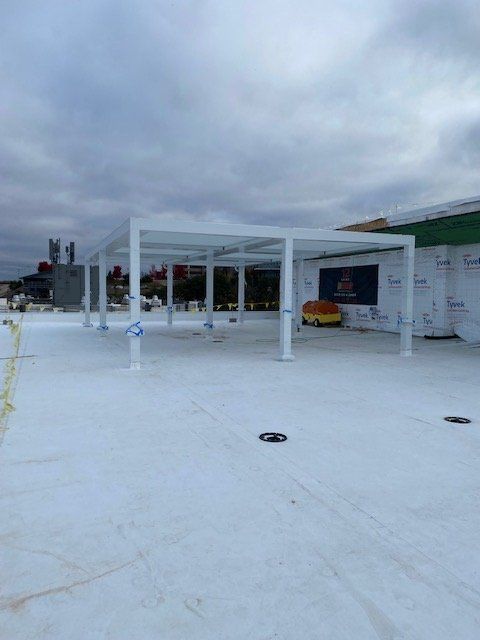 White pergola frame on a white surface, construction site. Cloudy sky in the background.