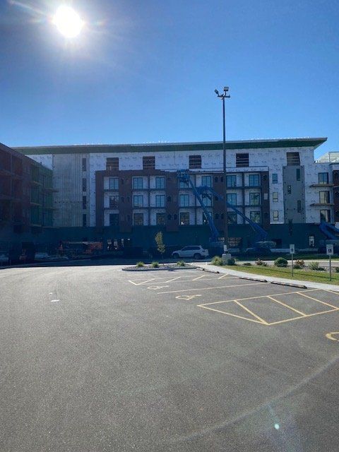 Building under construction on a sunny day. Parking lot in foreground.