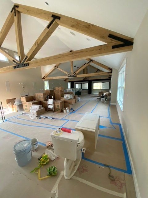 Interior of a room under construction with exposed wooden beams, tape, boxes, and a toilet.