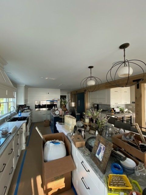 Kitchen under renovation with white cabinets, dark sink, and two pendant lights.