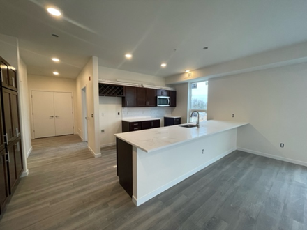 Modern kitchen with white countertops, dark cabinets, and gray flooring.