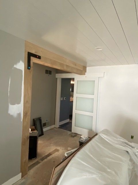 Interior view of doorway with unfinished wood trim, frosted sliding door, and black metal bracket.