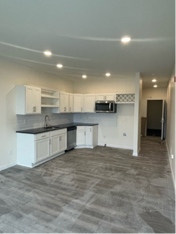 Modern kitchen with white cabinets, black countertops, and stainless steel appliances.