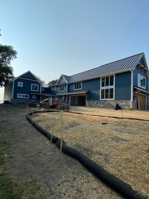 Blue house under construction with stone accents and a metal roof.