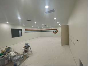 Empty room with painted walls and a retro design, unfinished flooring, and construction supplies.