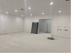 Empty room with white walls and ceiling. Metal stairs in the center, doorway to the right.