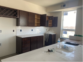 Kitchen with dark brown cabinets, white subway tile backsplash, and light countertops.