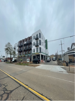 Multistory apartment building under cloudy sky on a city street.