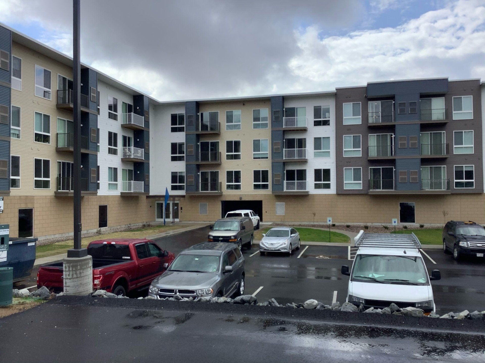 Apartment building with cars parked in front on a cloudy day.