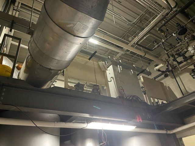Industrial setting: pipes, wiring, and metal beams in a ceiling, likely for utility and infrastructure.