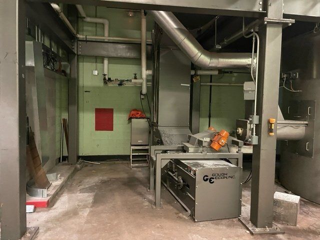 Industrial equipment in a room with pipes, ducts, and metallic structures.