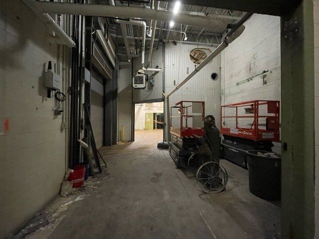 Interior of a warehouse or industrial space with equipment and a person standing next to a scissor lift.